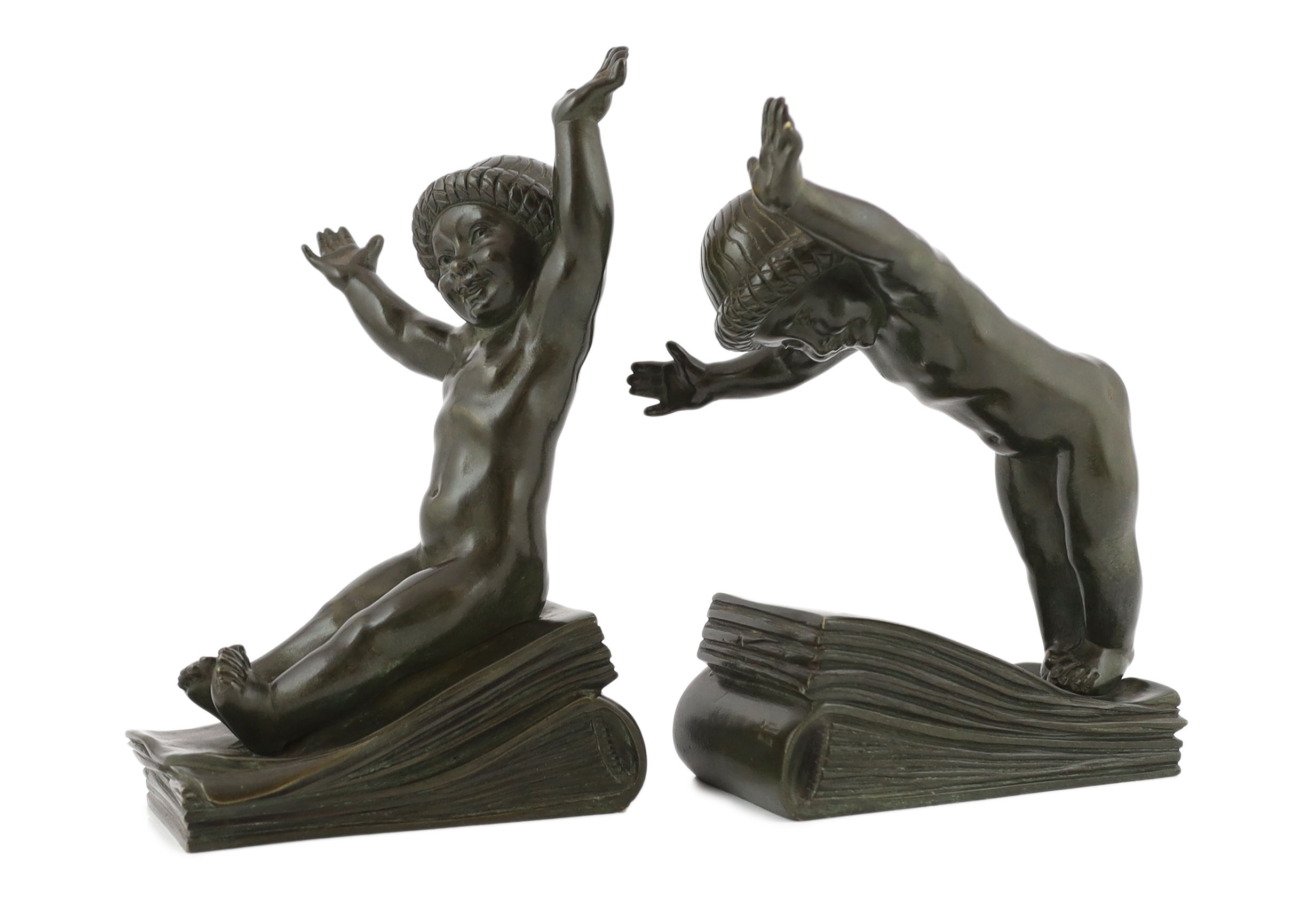 Claude (Claude-Marie Devenet 1851-1931), a pair of French Art Deco bronze bookends, Marcel Guillemard foundry mark, modelled as smiling naked infants standing upon ledgers, signed in the bronze, 16cm wide, 25cm high